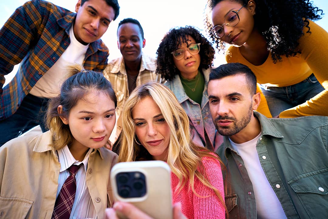 A group of friends looking together at something in a phone.